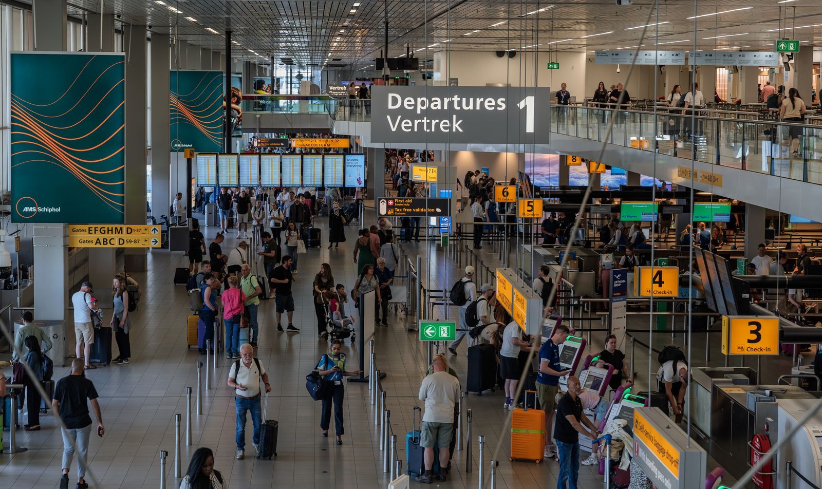 Travelers with suitcases crossing a busy airport departures hall under check-in signs, the setting for many common travel questions