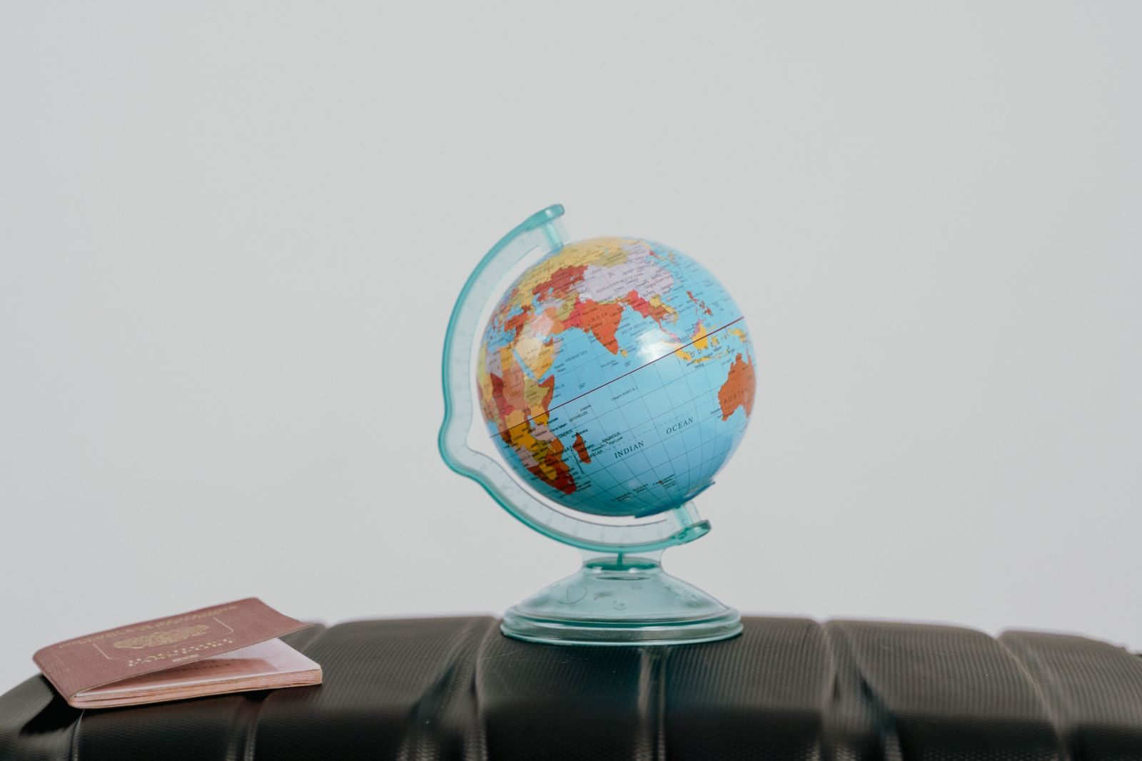 Two passports lying on a suitcase beside a small desk globe