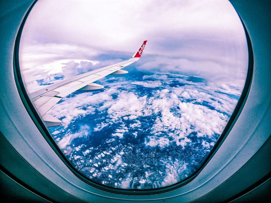 Airplane wing and clouds seen through a round cabin window on a long flight